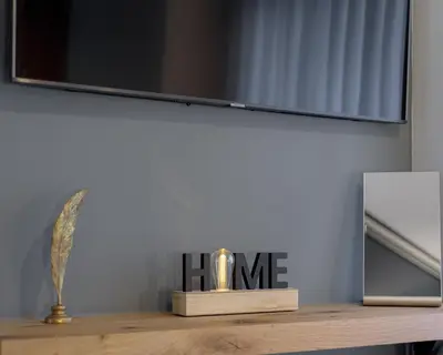 a clock on a wooden table with a television at Acropolis Deluxe Apartment in Athens