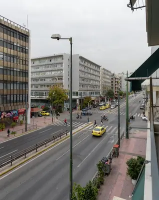 a city street with a yellow car driving down the road at Acropolis Deluxe Apartment in Athens