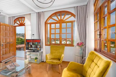 a living room with two yellow chairs and a table at Villa Artemida Vravrona in Vravrona