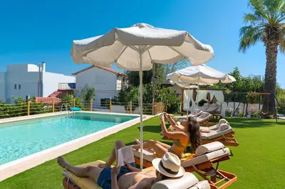 a group of people laying in lawn chairs next to a pool at Villa Artemida Vravrona in Vravrona