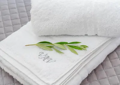 a pile of towels with a green leaf on top at Villa Artemida Vravrona in Vravrona