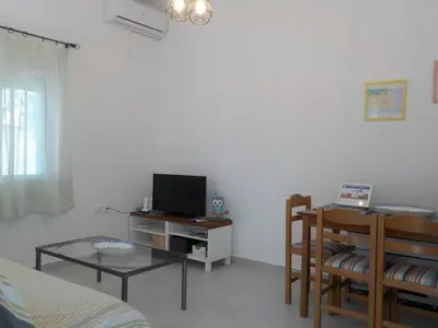 a living room with a bed and a tv and a table at Casa Aqua Marina in Aghia Marina