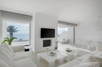 a white living room with a white couch and a tv at Luxurious Beachfront Villa Maira in Aghia Marina