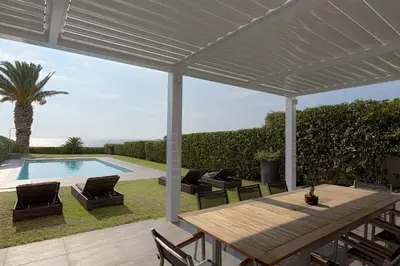 a patio with a wooden table and chairs and a pool at Luxurious Beachfront Villa Maira in Aghia Marina