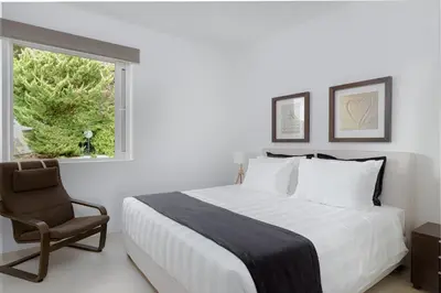 a bedroom with a bed and a chair and a window at Luxurious Beachfront Villa Maira in Aghia Marina