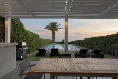 a patio with a table and chairs and a pool at Luxurious Beachfront Villa Maira in Aghia Marina