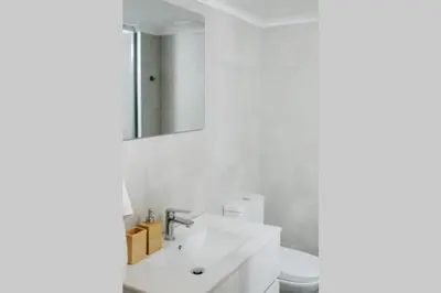 a white bathroom with a sink and a mirror at Newly Renovated Athenian Apt with Balcony in Athens