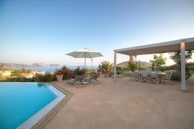 a patio with a table and an umbrella and a pool at LYCIPONON Villa in Anavissos