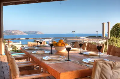 a wooden table with wine glasses and a bowl of fruit at LYCIPONON Villa in Anavissos