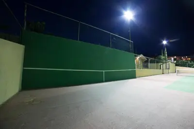 a tennis court with a green wall at night at LYCIPONON Villa in Anavissos