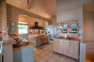 a large kitchen with white appliances and wooden walls at LYCIPONON Villa in Anavissos