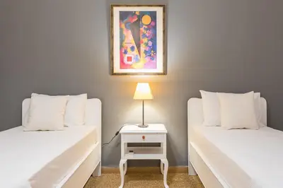 a room with two beds and a table with a lamp at Private Rooms Athens - Shared Bathroom in Athens