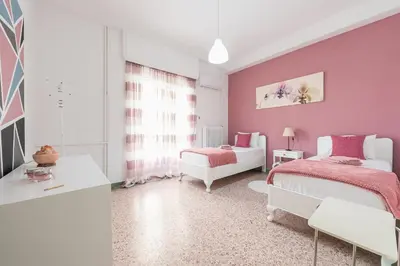 a bedroom with two beds and pink walls at Private Rooms Athens - Shared Bathroom in Athens