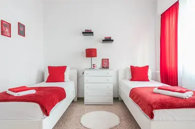 two beds in a white room with red curtains at Private Rooms Athens - Shared Bathroom in Athens