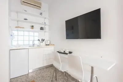 a white kitchen with a tv on a wall at Blue Couple House Athens in Athens