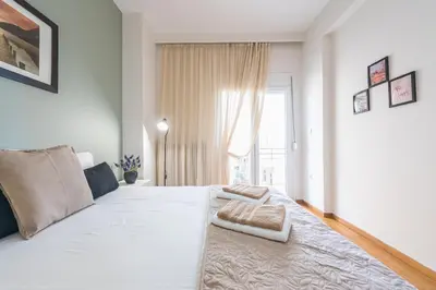 a bedroom with a large white bed with a window at Sophisticated Family House With Acropolis View in Athens