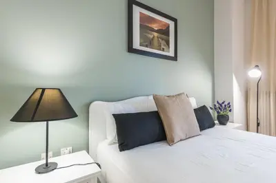 a bedroom with a white bed with a lamp on a table at Sophisticated Family House With Acropolis View in Athens