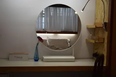 a round mirror on a desk with a vase and a window at h2h Myrto #Λειτουργικό studio 30' Αθήνα, 15' Αεροδρομιο in Athens