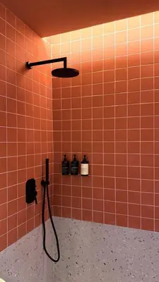 a red tiled bathroom with a shower with bottles on the wall at Sea View Beach Penthouse - Athens Coast in Athens