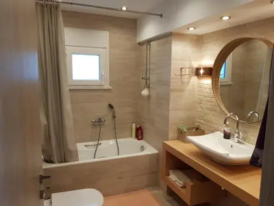 a bathroom with a tub and a sink and a mirror at Casa Denva in Kalívia Thorikoú