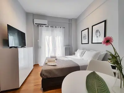 a white bedroom with a bed and a tv at Zea Apartments in Piraeus