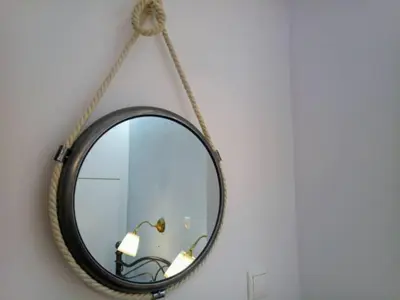 a mirror hanging on a wall with a rope at Freatida apartment in Piraeus