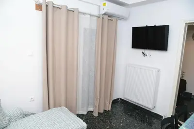 a room with curtains and a tv on a wall at Freatida apartment in Piraeus