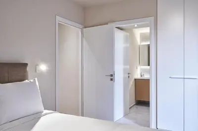 a bedroom with white walls and a bed and a bathroom at Charitos IΧ, Chic n modern 2BD Apt in Athens