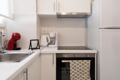 a small kitchen with white cabinets and a stove at Urban Boho apartment in Koukaki in Athens