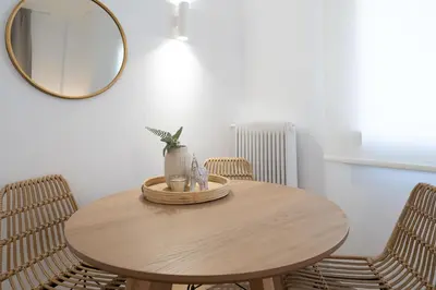 a round wooden table with chairs and a mirror at Urban Boho apartment in Koukaki in Athens