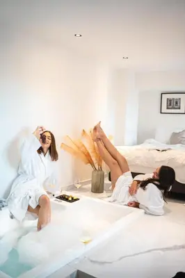 two women laying in a bath tub in a hotel room at Melo Athens in Athens