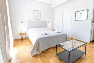 a white bedroom with a bed and a glass table at Filoxenia MG Kolonaki Athens in Athens