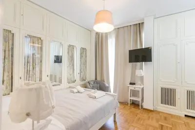 a white bedroom with a bed and a tv at Filoxenia MG Kolonaki Athens in Athens