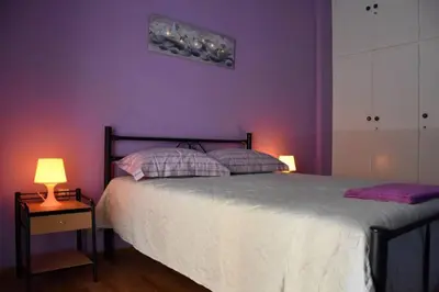 a bedroom with purple walls and a bed with two lamps at Colourful Apartment in AthensCity 1min from Subway in Athens