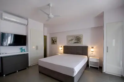 a white bedroom with a large bed and a sink at SYNATHENS APARTMENTS & STUDIOS in Athens