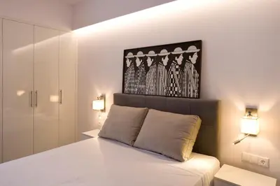 a bedroom with a white bed with two lights at SYNATHENS APARTMENTS & STUDIOS in Athens