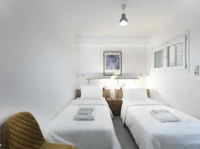 a room with three beds and a chair in it at 2 bedroom aprtmnt next to Hilton and all hospitals in Athens