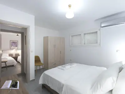 a white bedroom with a bed and a desk at 2 bedroom aprtmnt next to Hilton and all hospitals in Athens