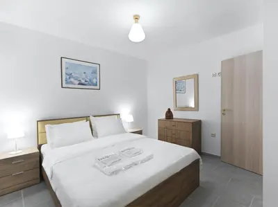 a bedroom with a large white bed and a cabinet at 2 bedroom aprtmnt next to Hilton and all hospitals in Athens