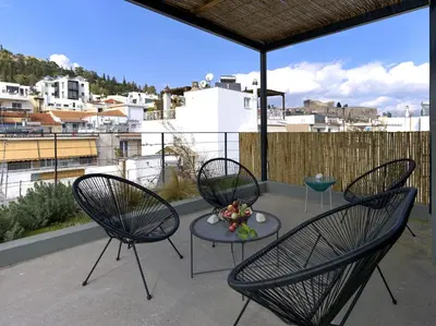 a patio with three chairs and a table on a balcony at Luxury Acropolis Rooftop Apartment in Athens