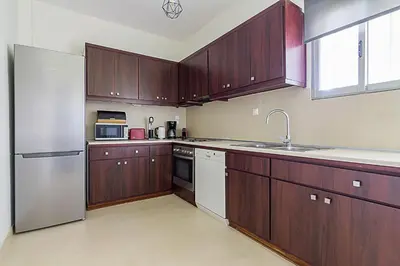 a kitchen with wooden cabinets and a stainless steel refrigerator at Two Bedroom Apartment in Chalandri with Balcony in Athens
