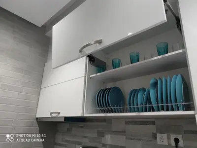 a white kitchen cabinet with blue dishes in it at Modern apartment with a huge terrace in Athens