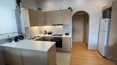 a kitchen with wooden cabinets and a white refrigerator at Elegant Glyfada Apartment-private Garden-Near METRO in Athens