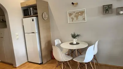 a table and chairs in a kitchen with a refrigerator at Elegant Glyfada Apartment-private Garden-Near METRO in Athens