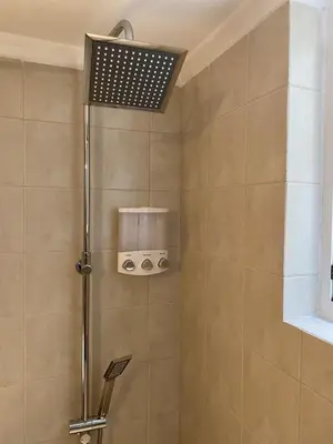 a shower with a shower head in a bathroom at Elegant Glyfada Apartment-private Garden-Near METRO in Athens