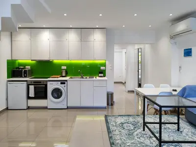 a kitchen with white cabinets and a green wall at KYMA Apartments Athens 18 in Athens