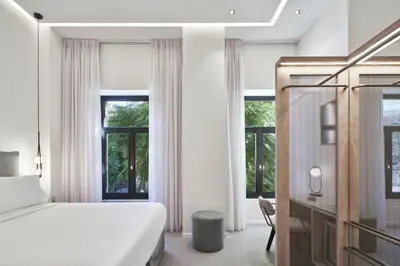a bedroom with a bed and a desk and windows at NLH MONASTIRAKI - Neighborhood Lifestyle Hotels in Athens