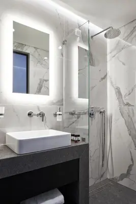 a bathroom with a sink and a glass shower at NLH MONASTIRAKI - Neighborhood Lifestyle Hotels in Athens
