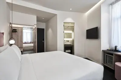 a white bedroom with a large bed and a television at NLH MONASTIRAKI - Neighborhood Lifestyle Hotels in Athens