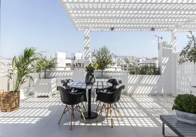 a patio with a table and chairs on a roof at Gallery Suites & Residences Piraeus in Piraeus